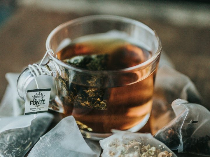 A small white cup of pale herbal tea on a wooden table