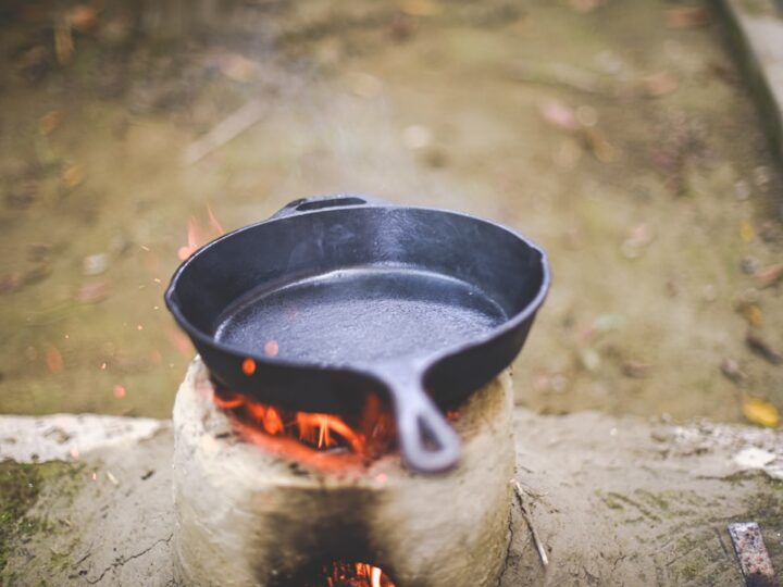A well-seasoned black cast iron skillet resting on a wooden kitchen counter beside a folded cotton cloth